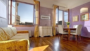 A room with a sofa, dining table, chairs, and a cabinet. - Magic Signoria Apartment  (Firenze)