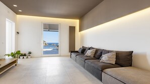 A modern living room with a sofa, a wooden table, and potted plants.