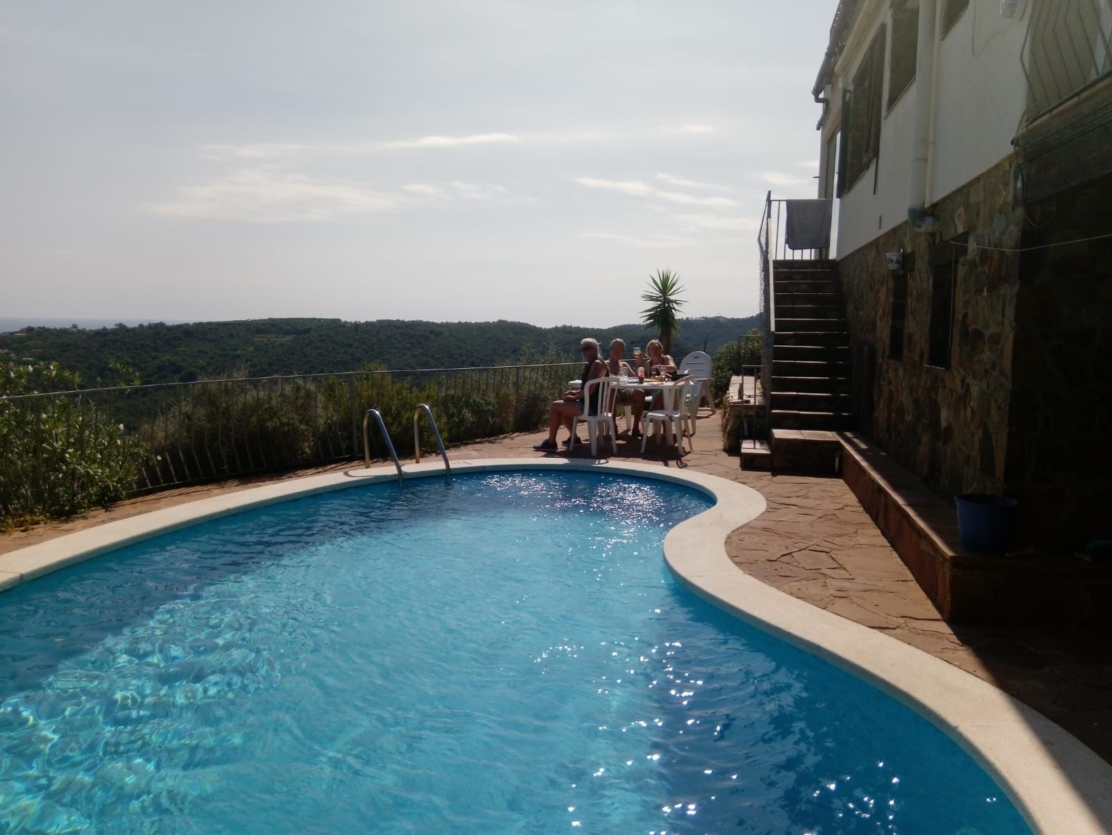 Une piscine à bord incurvé, un mur en pierre et un escalier menant à un niveau supérieur.