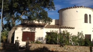 Un bâtiment doté d’une tour ronde, d’un mur en pierre et d’un arbre.