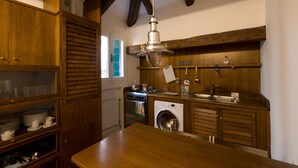 Een keuken met houten kastjes, een wasmachine, een spoelbak en een hanglamp.