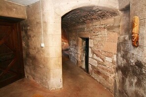 A narrow stone corridor with a wooden door on the left and a wooden sculpture on the right. - medieval castle. exclusive use of the grounds and castle  (Arbroath)