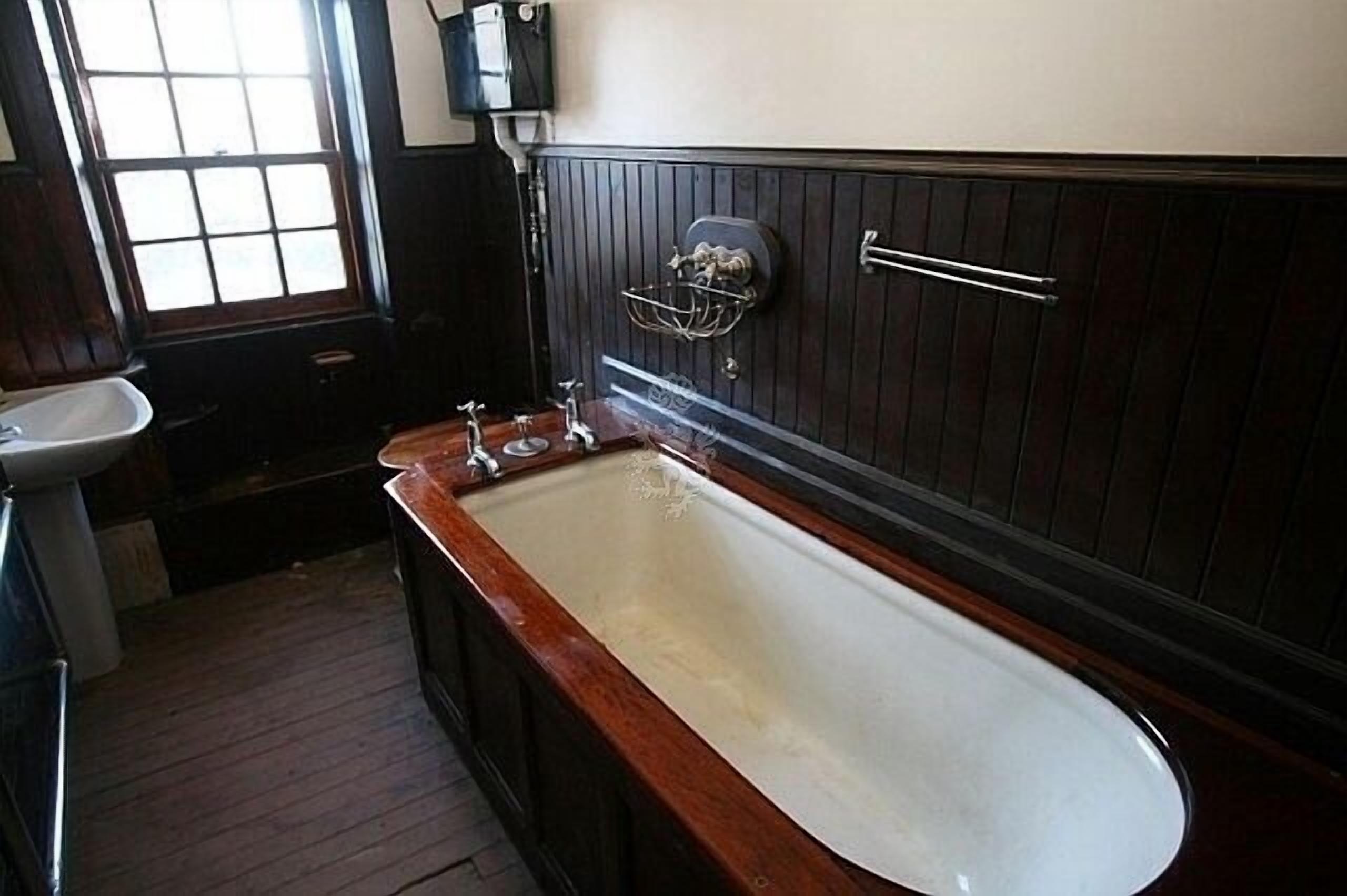 A bathroom with a wooden vanity, a white sink, and a large bathtub.