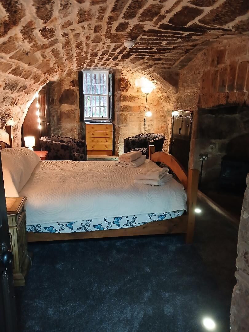 Een slaapkamer met stenen muren, een bed, een kaptafel en een raam.