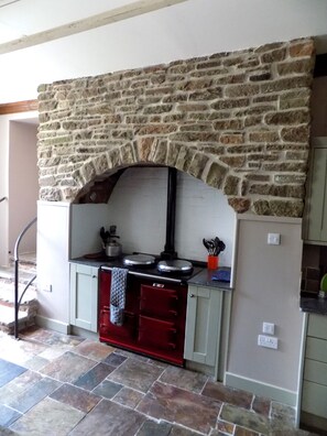 A stone fireplace with a built-in oven, a red oven door, and a countertop with kitchen utensils. - medieval castle. exclusive use of the grounds and castle  (Arbroath)