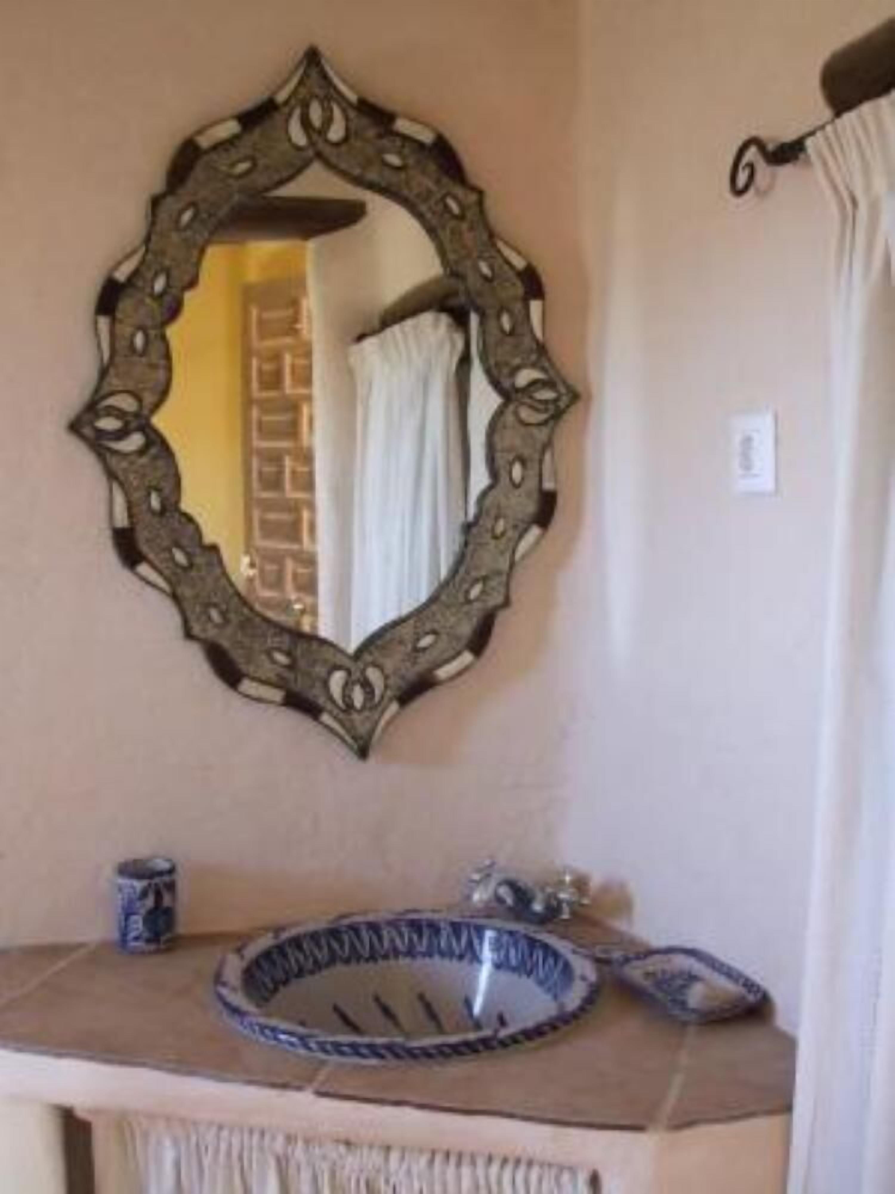 A bathroom with a decorative mirror, a sink with a blue and white bowl, and a towel hanging on a rack.