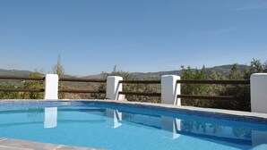 A clear blue swimming pool with a wooden fence and white pillars, surrounded by greenery and hills in the background. - Beautiful Farmhouse, Private Pool, Stunning Views Free Wifi, Historic Montefrio (Montefrio)