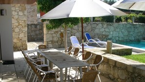 An outdoor patio with a stone wall, a pool, and lounge chairs. - Elegant Villa, Caminha. Pool & large garden. Near market towns & beaches. (Caminha)