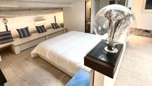 Ein modernes Schlafzimmer mit Dachfenster, einem Bett, einer Bank mit Kissen und einem Tisch mit Lampe.