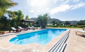 Relax by the pool surrounded by lush greenery and distant mountains.