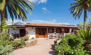 Traditional colonial-style building with a central patio area surrounded by lush greenery and palm trees.