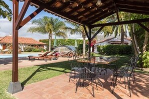 Relax in a serene outdoor space surrounded by lush greenery and palm trees, with a patio table and chairs.