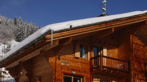 Een houten chalet met een balkon, een houten deur en een trap naar de ingang.