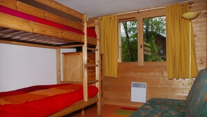 Een houten kamer met stapelbedden, een raam met gordijnen en een radiator.