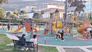 Une aire de jeux dotée de diverses installations, notamment des toboggans et des balançoires, entourée d’une zone dallée avec des bancs.