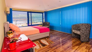 Une chambre à coucher avec un lit, une chaise, un bureau et une fenêtre donnant sur un paysage agréable.