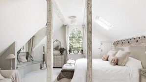 A bedroom with a large bed, a window, and a staircase.