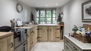 A kitchen with wooden cabinets, a built-in oven, a sink, and a window with a view of greenery.