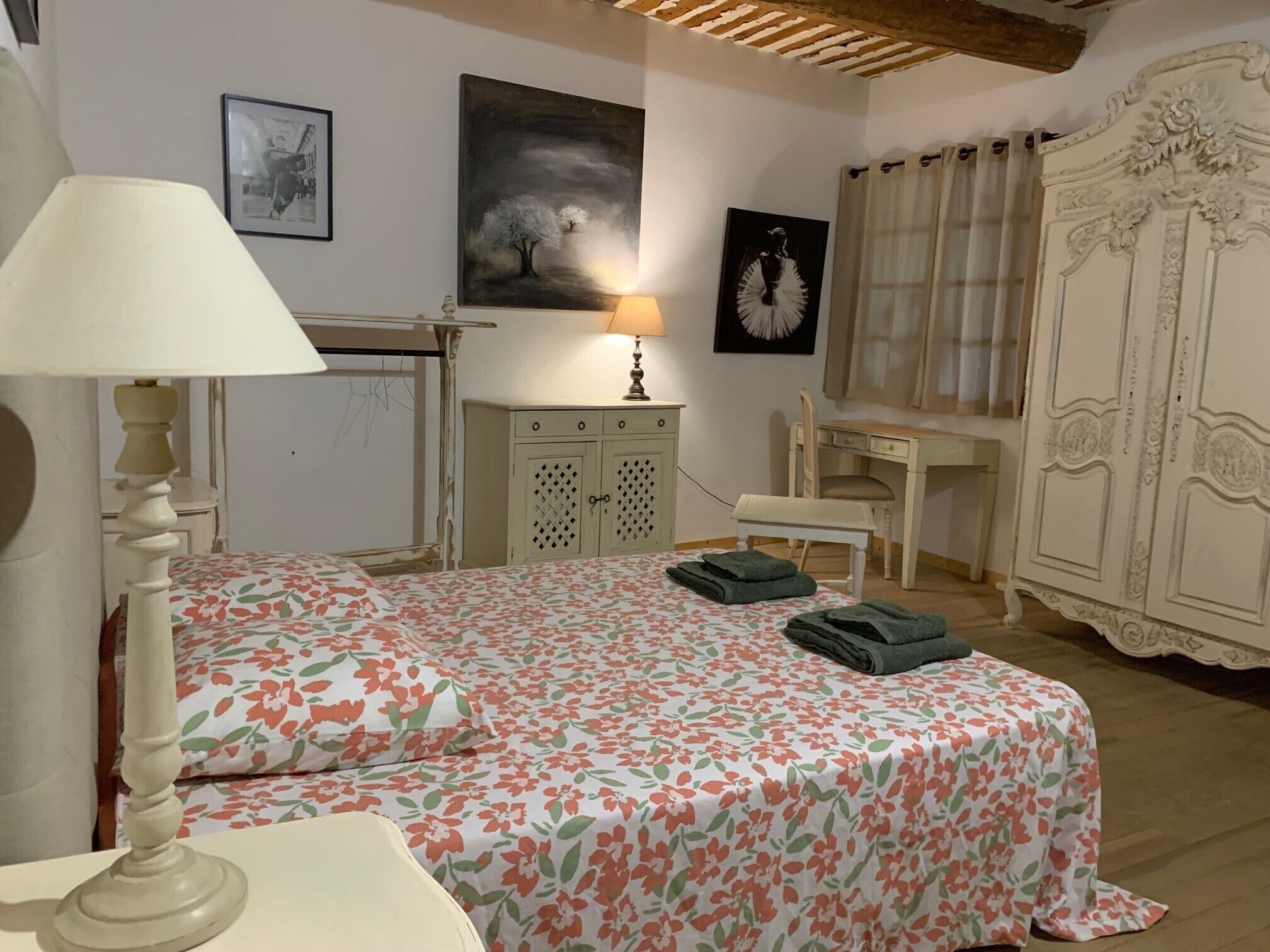 A bedroom with a bed, a desk, a chair, a wardrobe, and a lamp.