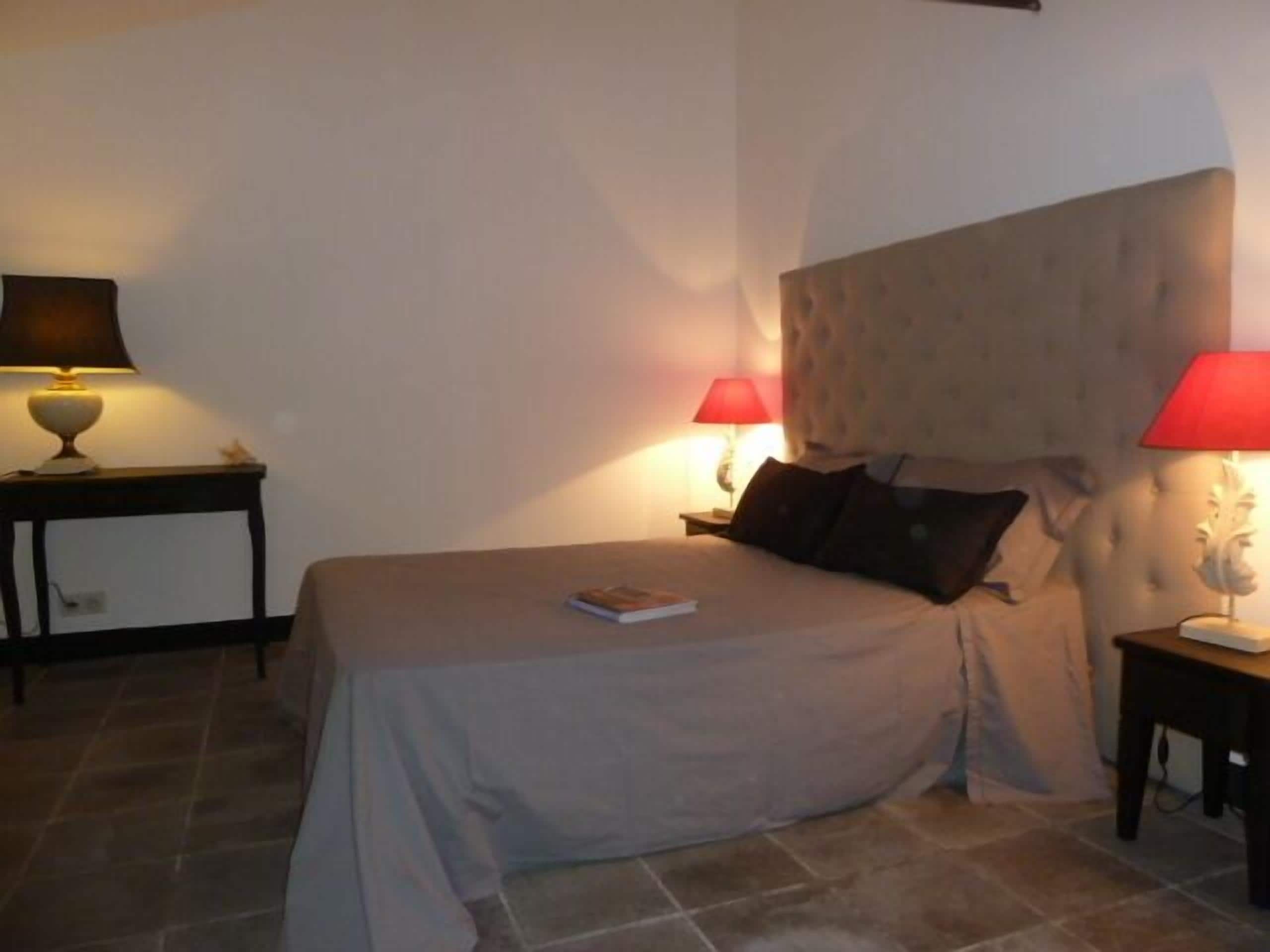 A bedroom with a bed, two bedside tables, and two lamps.