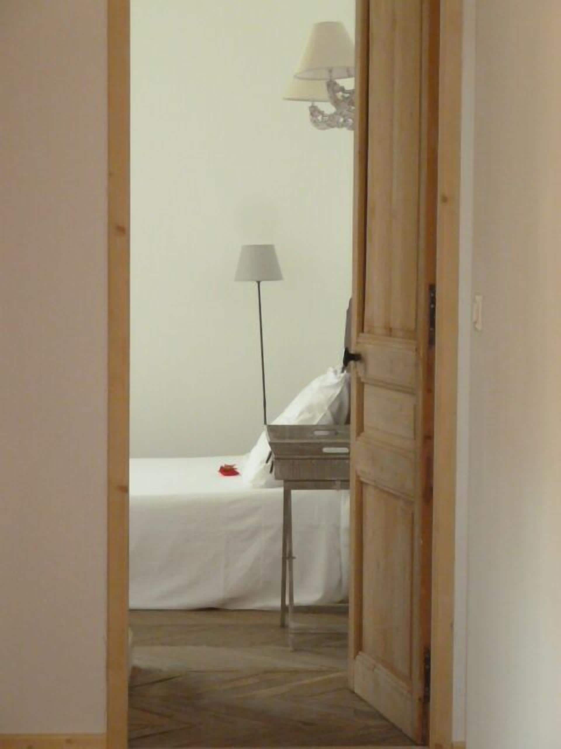A room with a bed, a bedside table, a lamp, and a wooden door.