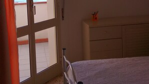 A bedroom with a bed, a door leading to a balcony, a wall-mounted air conditioner, and a small shelf with items. - Noto Lido (Syracuse Sicily Italy), Adriana Residence on the Beach by the Sea !!! (Lido di Noto)