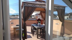 Eine Terrasse mit Tisch und Stühlen, einem Grill und Blick auf die Stadt.