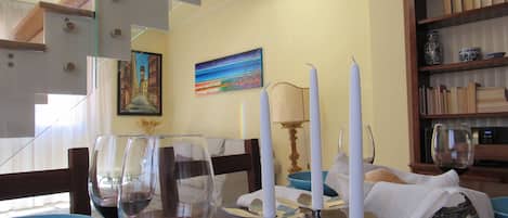 A dining area with a table set for two, featuring wine glasses and a candle holder.