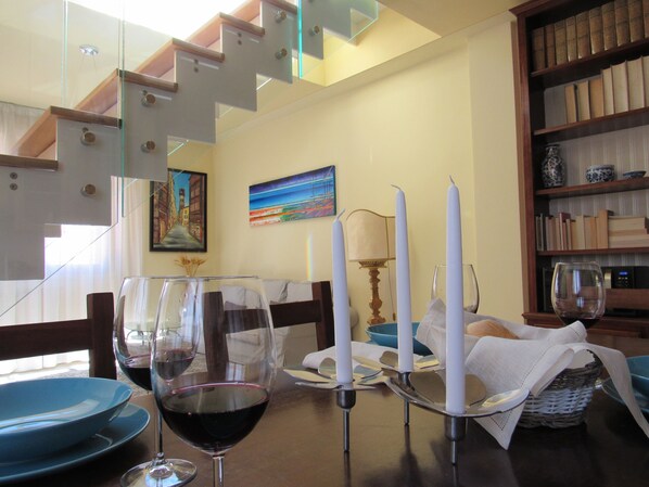 A dining area with a table set for two, featuring wine glasses and a candle holder.
