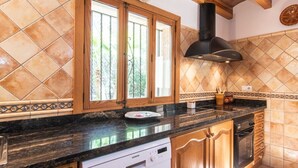 Cozinha com armários de madeira, bancada preta, lava-louças Siemens e exaustor preto.