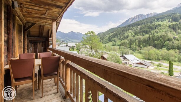 A wooden balcony with chairs and a view of a valley and mountains. - Renovated old farmhouse, chalet with decor that combines charm and tradition (Abondance)