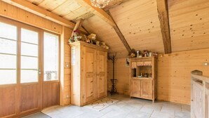 A wooden interior with a high ceiling, a large wooden door, and a tiled floor. - Renovated old farmhouse, chalet with decor that combines charm and tradition (Abondance)