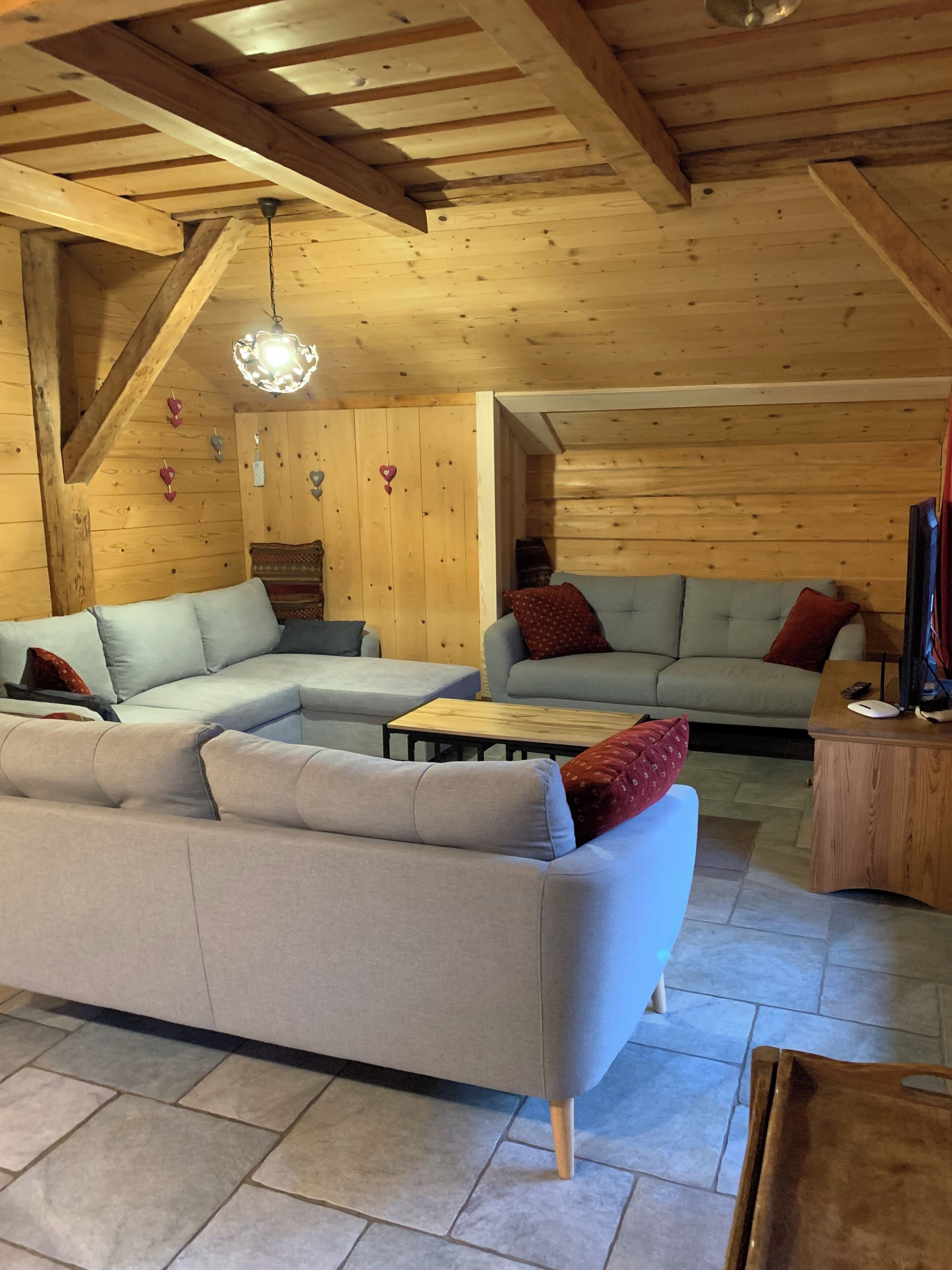Ein gemütliches Holzinterieur mit einer Eckcouch, einem kleinen Couchtisch und einem Fernseher auf einem Holzgestell.