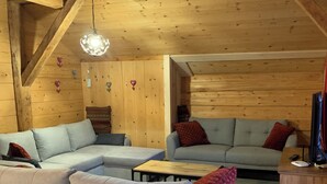 A cozy wooden interior with a sectional sofa, a small coffee table, and a TV on a wooden stand. - Renovated old farmhouse, chalet with decor that combines charm and tradition (Abondance)