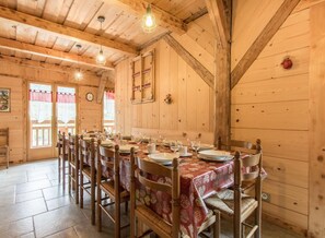 A wooden dining room with a long table set for a meal, wooden chairs, and a clock on the wall. - Renovated old farmhouse, chalet with decor that combines charm and tradition (Abondance)