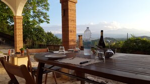 An outdoor dining area with a brick pillar, a table set with plates, glasses, and a bottle of water. - Edge of Nature Reserve; a/c   5* views. Great peace & privacy. Mountains & Sea. (ATRI)
