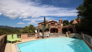 A pool area with lounge chairs, a stone building, and a mountainous backdrop. - mansion - 8 rooms - 12/13 persons (Porto Vecchio)