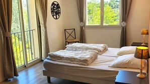 Una camera da letto con un letto, una finestra con tende, un comodino con una lampada e una decorazione a parete.