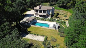 Una casa a due piani con piscina, immersa in una fitta foresta.