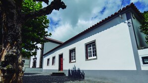 A building with a red door, white walls, and a tiled roof. - OLD CHURCH HOUSE  (FURNAS)