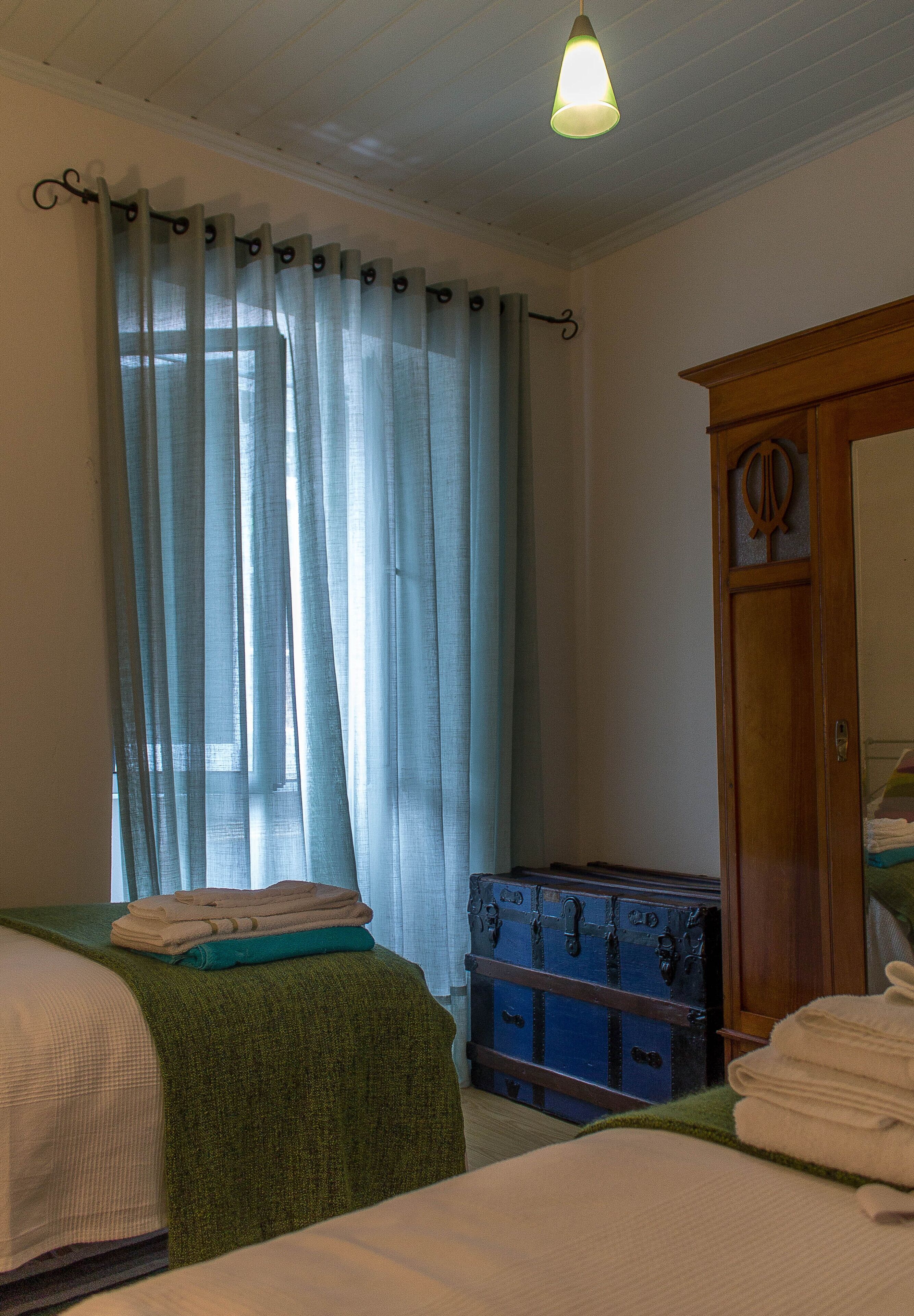 Ein Zimmer mit zwei Betten, einem Holzschrank und einem blauen Koffer.