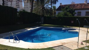 A rectangular swimming pool with a diving board, surrounded by a well-maintained lawn and a stone pathway. - 4 Bedroom Townhouse With Pool Close To Town, Beach And Park - Free WiFi (Benalmadena Cost)