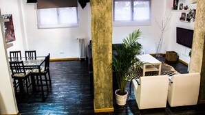 Un salón amplio con una mesa de comedor, sillas, un sofá y una planta grande en maceta.