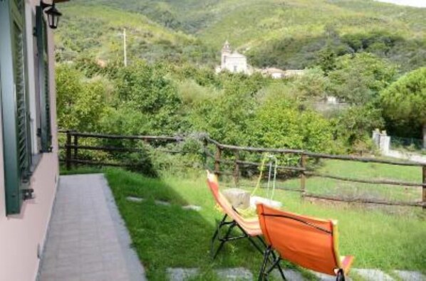 A balcony with a view of a lush green landscape and a distant building.