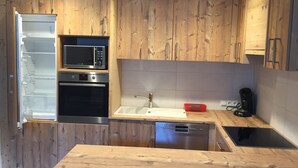 A modern kitchen with wooden cabinets, a built-in microwave, oven, dishwasher, and a sink. - Convenient modern apartment in Soell, close to the ski lift (Söll)