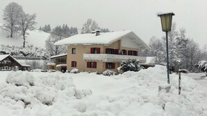 A two-story house with a snow-covered roof and a balcony. - Convenient modern apartment in Soell, close to the ski lift (Söll)