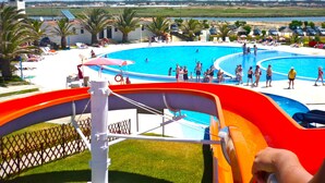 Area piscina con scivolo acquatico, lettini e vista sul paesaggio circostante.