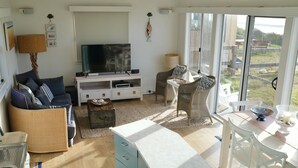 Un salon comprenant un téléviseur, un canapé et un coin repas avec des chaises et une table.