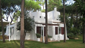 A modern white house with a covered patio, surrounded by trees and a grassy yard. - Luxury villa with large garden and pool, next to the golf course and near the beach (Vilamoura)