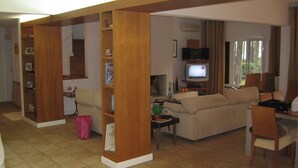 A living room with a sofa, a television, a coffee table, and a bookshelf. - Luxury villa with large garden and pool, next to the golf course and near the beach (Vilamoura)
